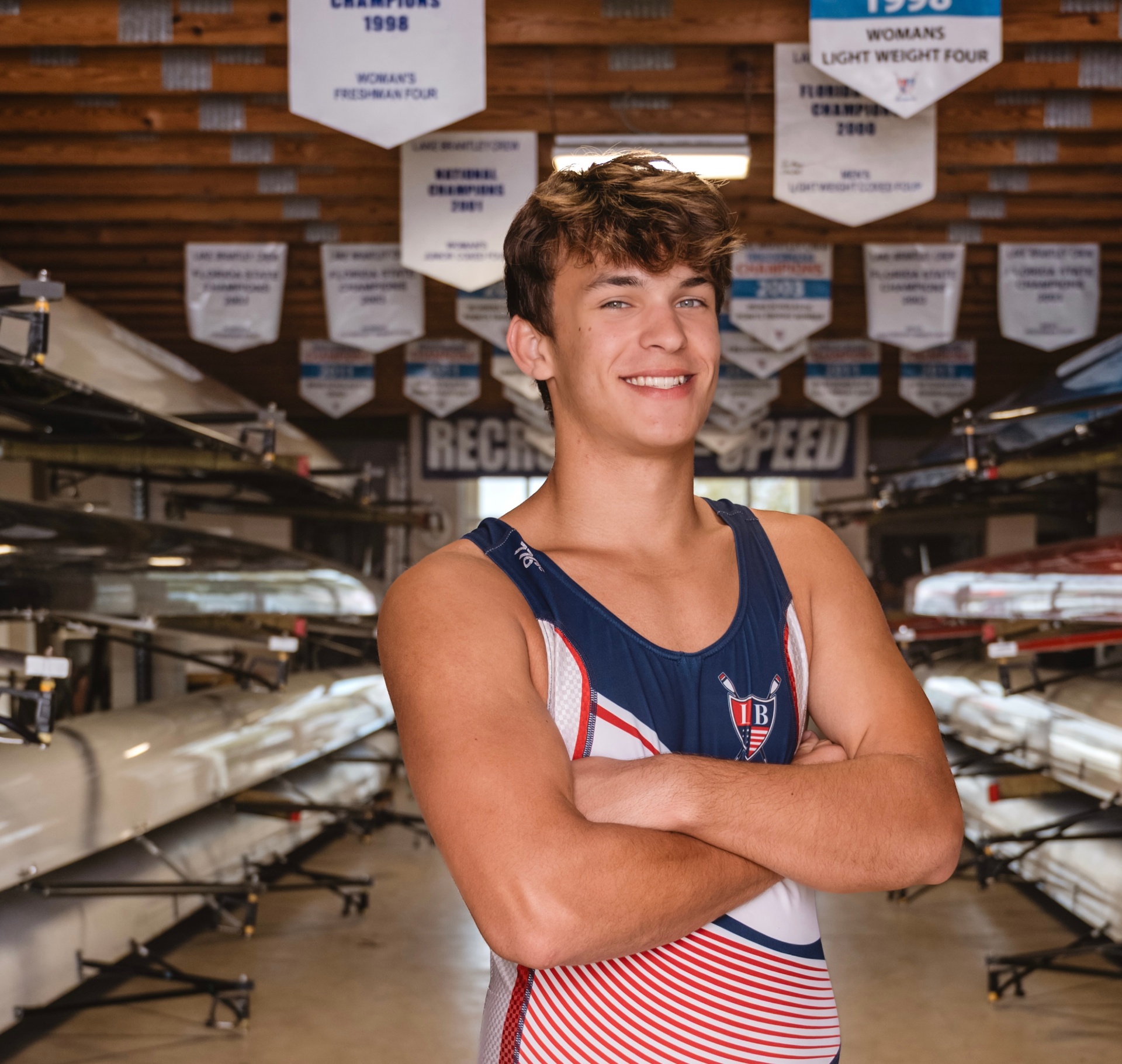 LBRA athlete beneath championship banners in the boathouse